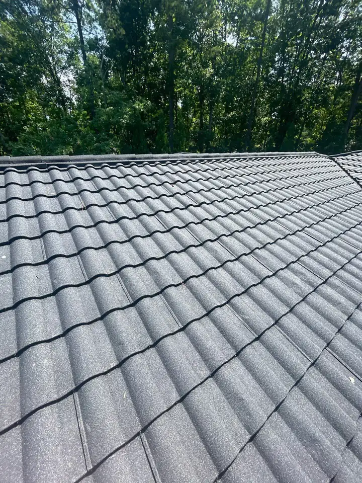 Charcoal stone-coated metal roof with a tile-style profile on a wooded Greater Rochester home